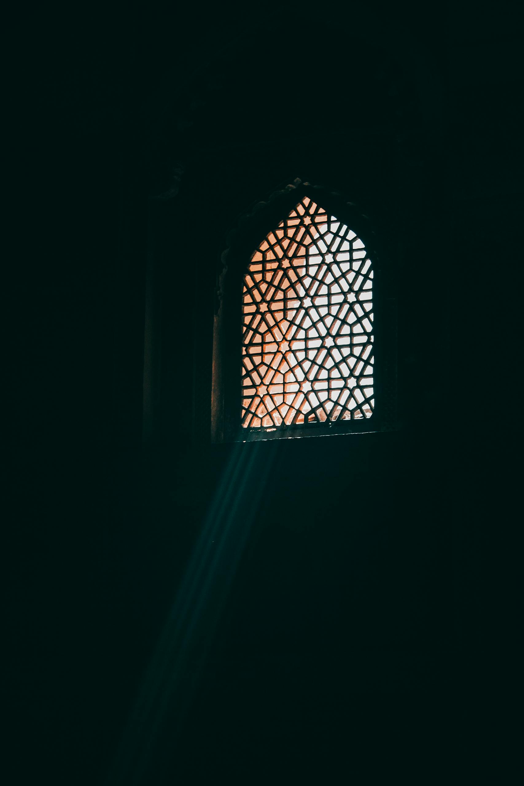 Sunlight streaming through a Mughal-style window in Agra, showcasing intricate Islamic architectural patterns.